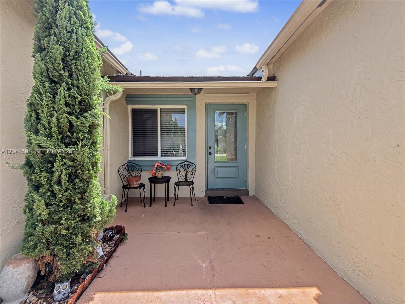 A small patio features a blue front door, a window, and two metal chairs — 13341 SW 114th Pl, Miami FL 33176, MIAMI, FL