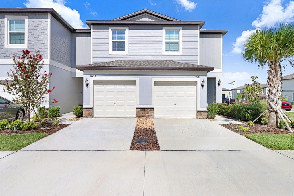 A two-story duplex with gray siding, two garage doors, and a concrete driveway — 10263 TRUMPET HONETSUCKLE WAY, SAN ANTONIO, FL
