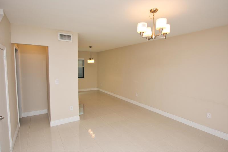 An empty room with beige walls, tile flooring, and two hanging light fixtures — 300 80th Street, Miami Beach FL 33141, MIAMI BEACH, FL