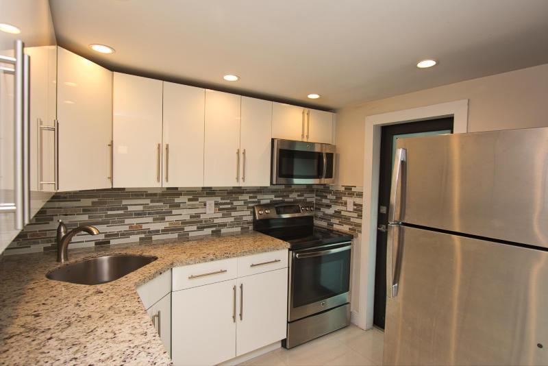 A kitchen features white cabinets, granite countertops, stainless steel appliances, and a mosaic tile backsplash — 300 80th Street, Miami Beach FL 33141, MIAMI BEACH, FL