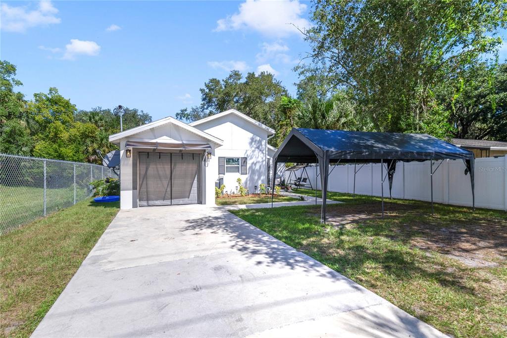 A white house with a garage, a concrete driveway, and a black metal carport — 1104 W 3RD STREET, SANFORD, FL