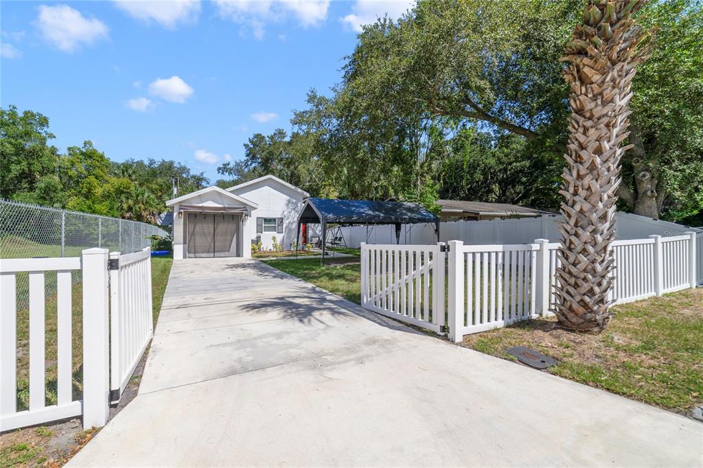 A white house with a concrete driveway, a carport, and a white vinyl fence — 1104 W 3RD STREET, SANFORD, FL