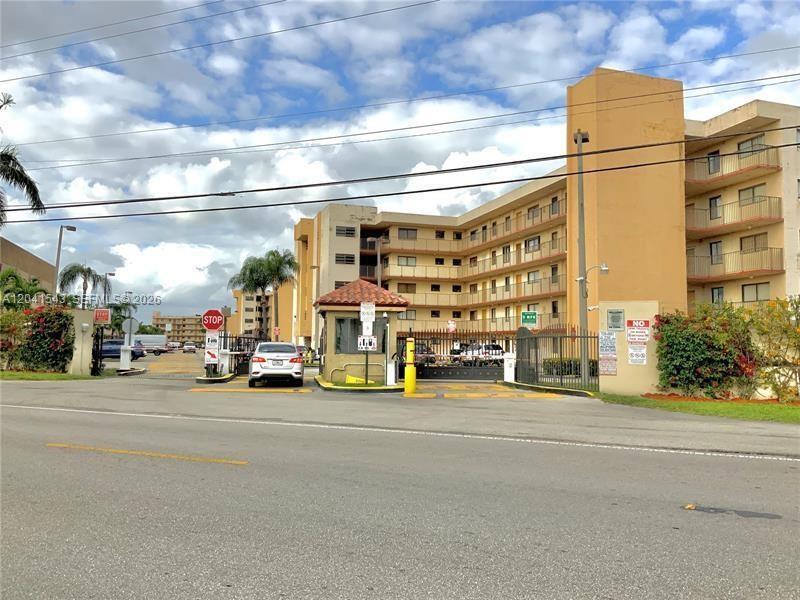 An exterior view of a multi-story apartment complex with a gated entrance and guard booth — 9915 W Okeechobee Rd # 404, Hialeah Gardens FL 33016, HIALEAH GARDENS, FL