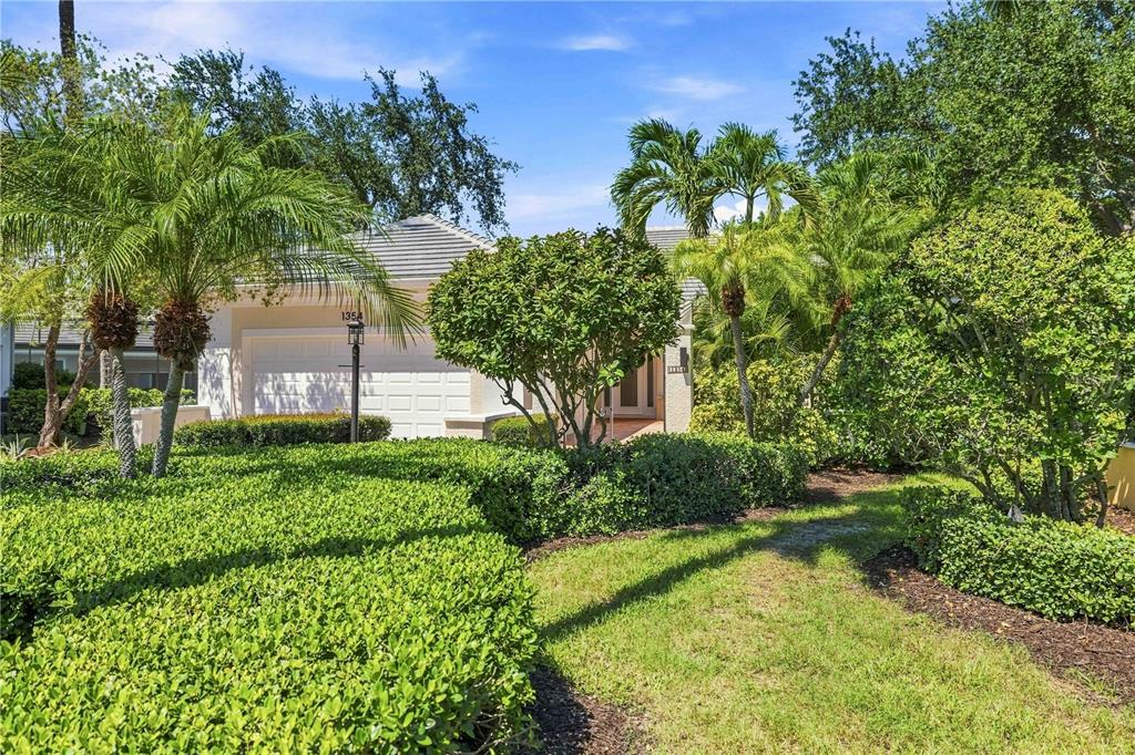 A single-story house with a white garage, palm trees, and manicured hedges in the front yard — 1354 TEAROSE PLACE, SARASOTA, FL
