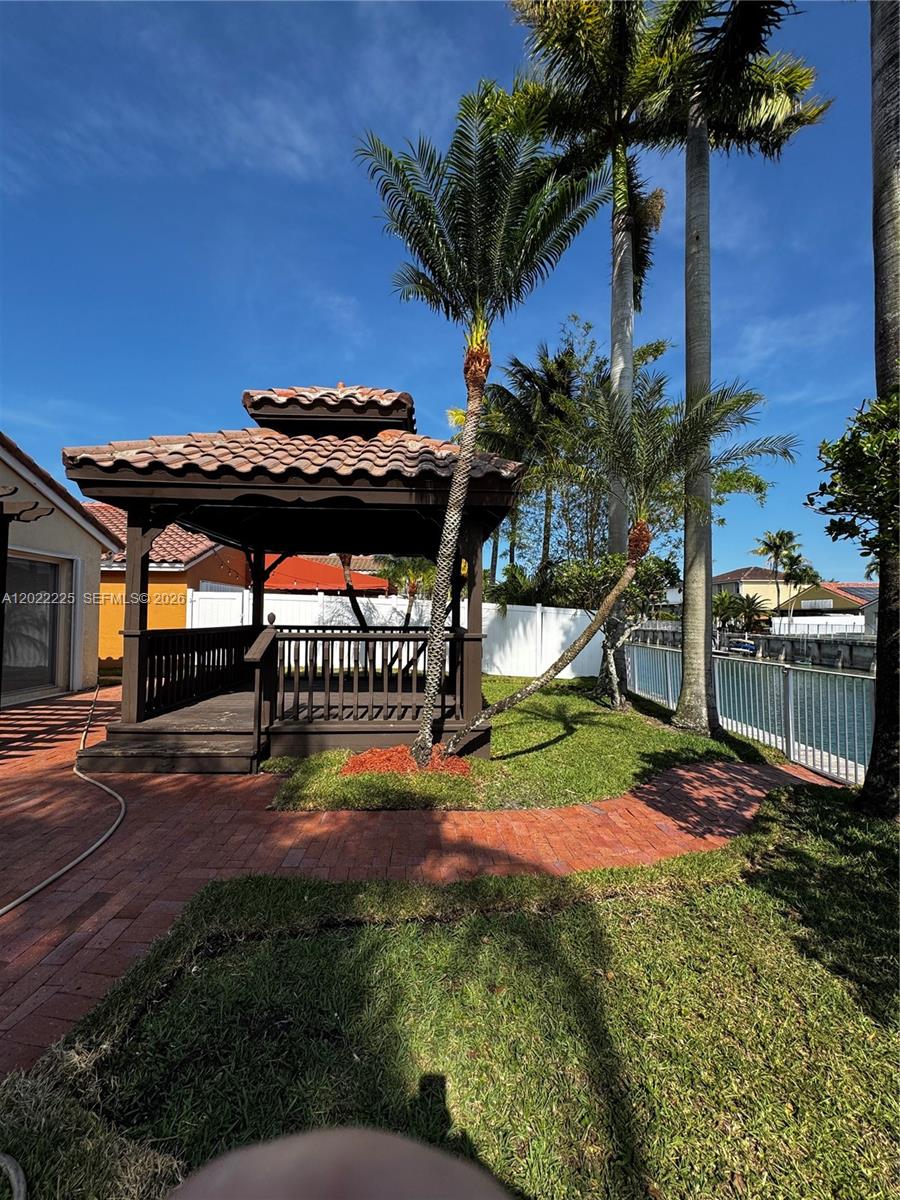 A wooden gazebo sits on a brick patio next to a canal and palm trees — 13312 SW 144th Ter, Miami FL 33186, MIAMI, FL
