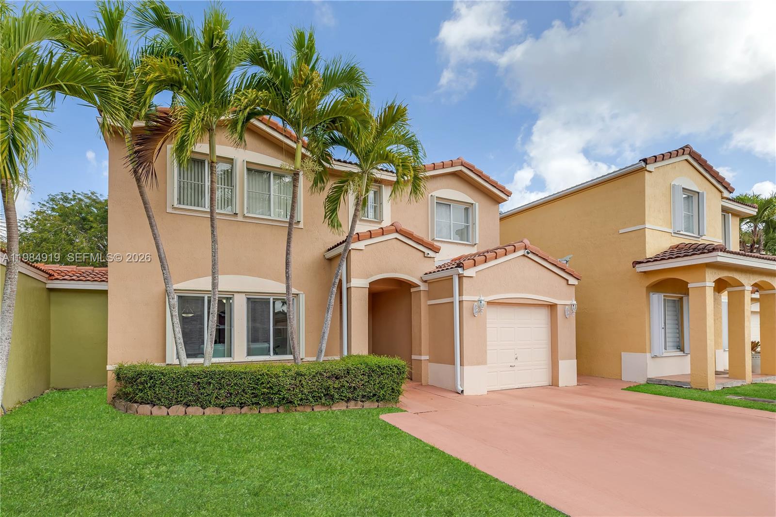 A two-story tan stucco house features a single-car garage, palm trees, and a manicured hedge — 16323 SW 97th St, Miami FL 33196, MIAMI, FL