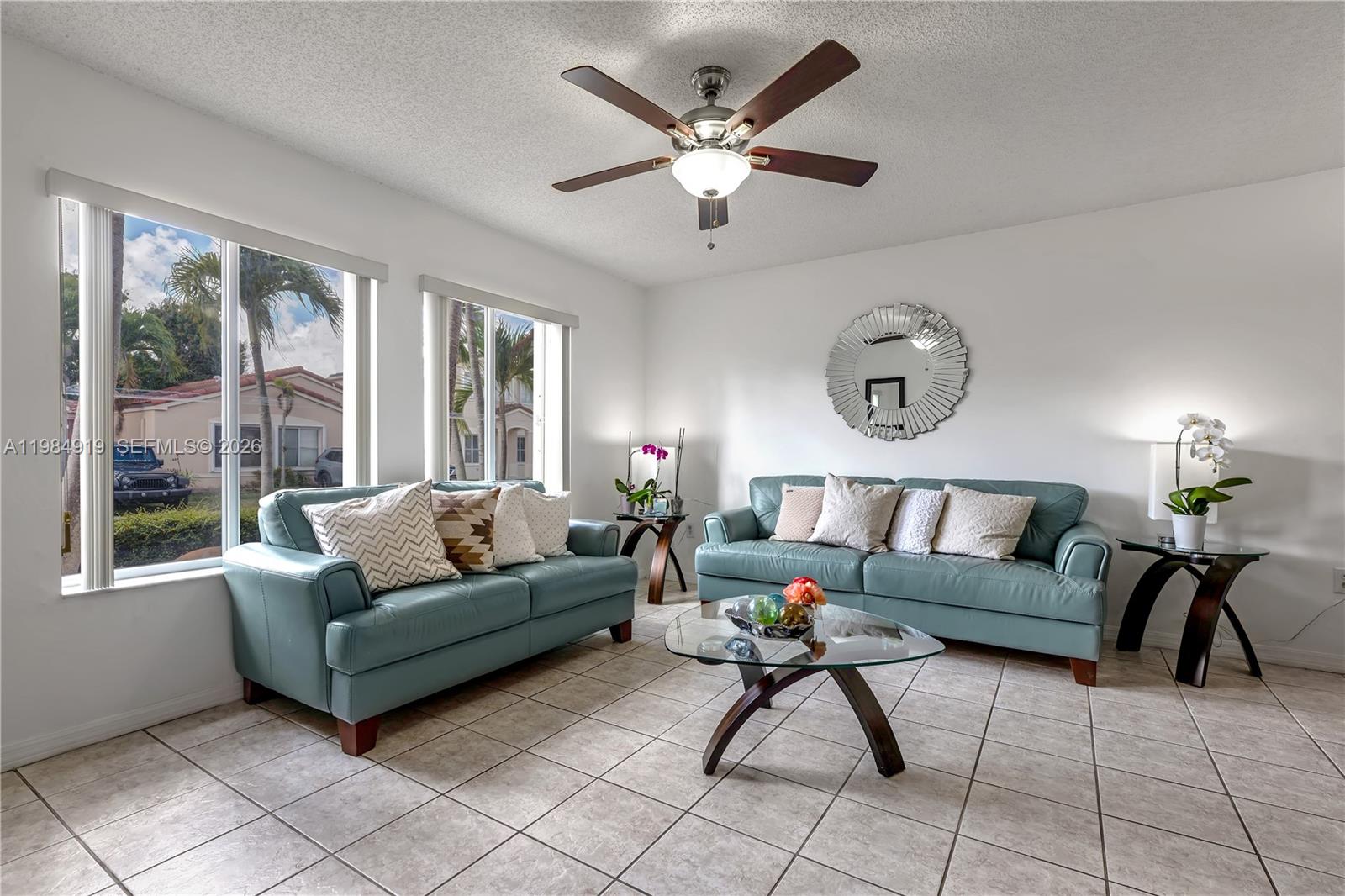 A living room features two teal leather sofas, a glass coffee table, and tiled floors — 16323 SW 97th St, Miami FL 33196, MIAMI, FL
