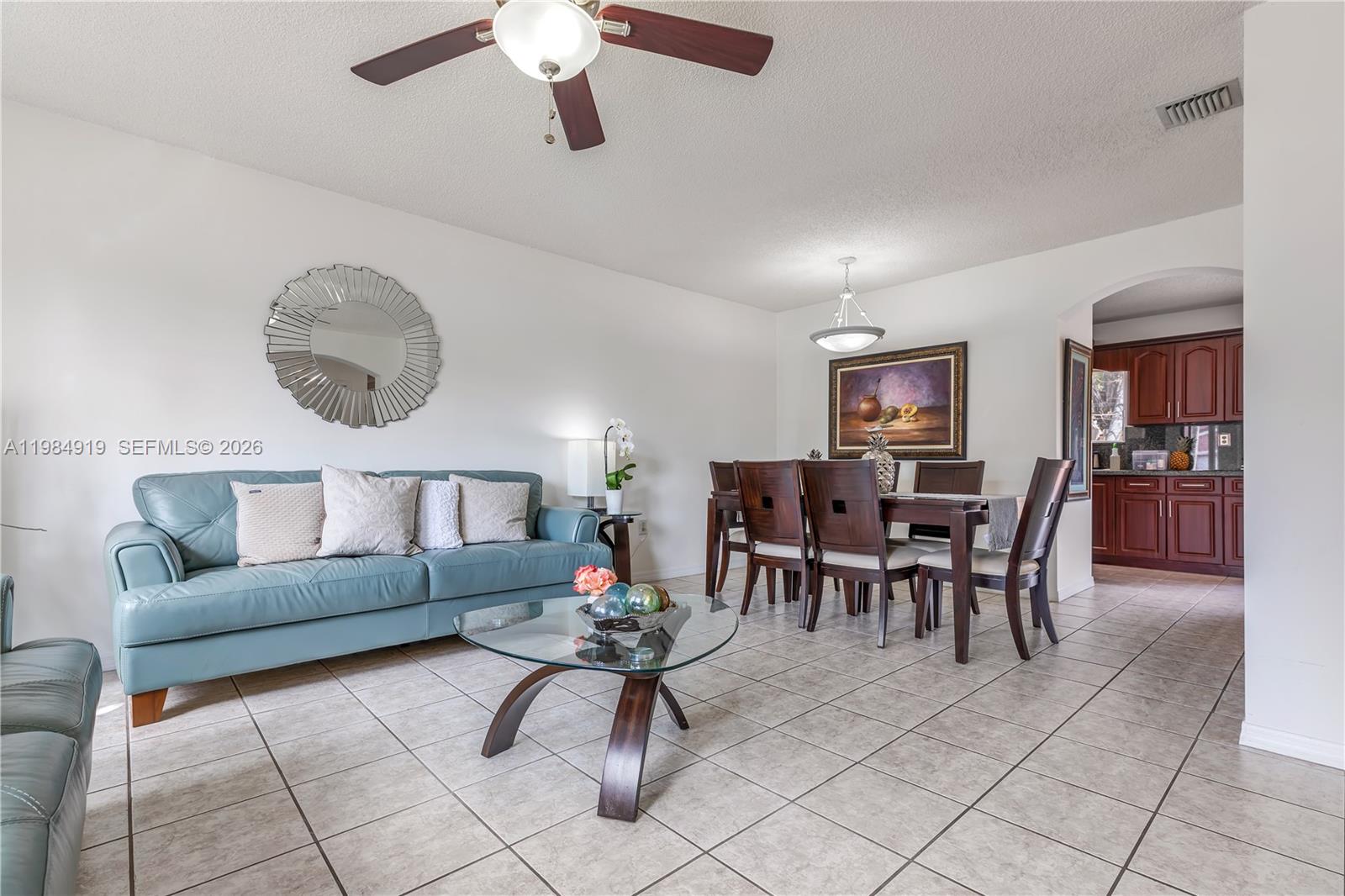 A living and dining area features a blue sofa, glass coffee table, and dark wood furniture — 16323 SW 97th St, Miami FL 33196, MIAMI, FL