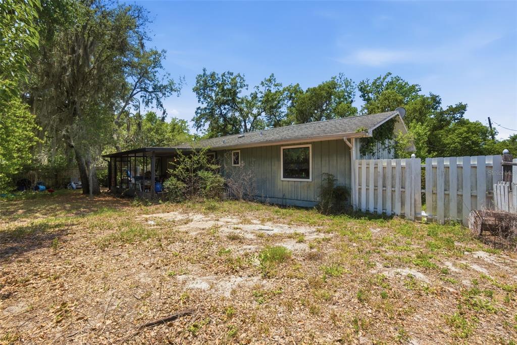 A single-story house with light green siding, a screened porch, and a white picket fence — 35724 DAWN DRIVE, LEESBURG, FL