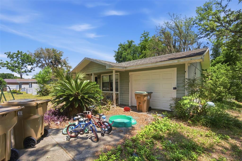 A light green house exterior with a garage, a driveway, and several children's bicycles — 35724 DAWN DRIVE, LEESBURG, FL