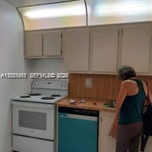 A kitchen features white cabinets, a white electric stove, and a teal dishwasher — MIAMI BEACH, FL