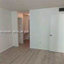 An interior view of a room with light wood-look flooring and a white door — MIAMI BEACH, FL