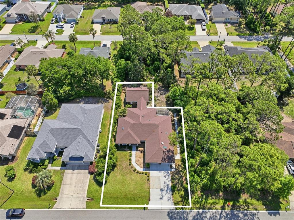 An aerial view shows a single-story house with a brown roof and a concrete driveway — 26 WOODBURY DRIVE, PALM COAST, FL