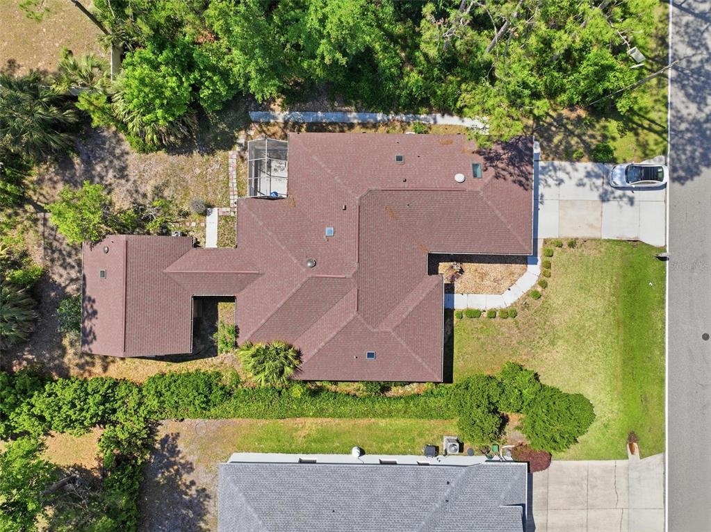 An aerial view shows a house with a brown shingled roof and a screened-in patio — 26 WOODBURY DRIVE, PALM COAST, FL