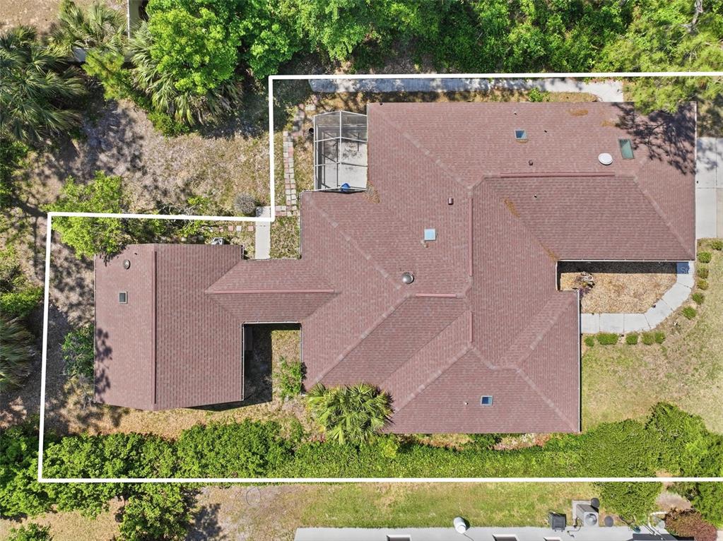 An aerial view shows a house with a brown shingled roof and a screened-in patio — 26 WOODBURY DRIVE, PALM COAST, FL