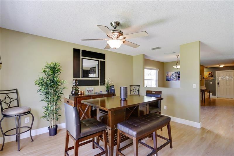 A dining area features a wooden table with chairs and a bench under a ceiling fan — 8008 SUTTON TERRACE LANE, TAMPA, FL