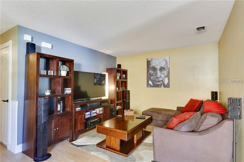 A living room features a dark wood entertainment center, a sectional sofa, and an Einstein portrait — 8008 SUTTON TERRACE LANE, TAMPA, FL