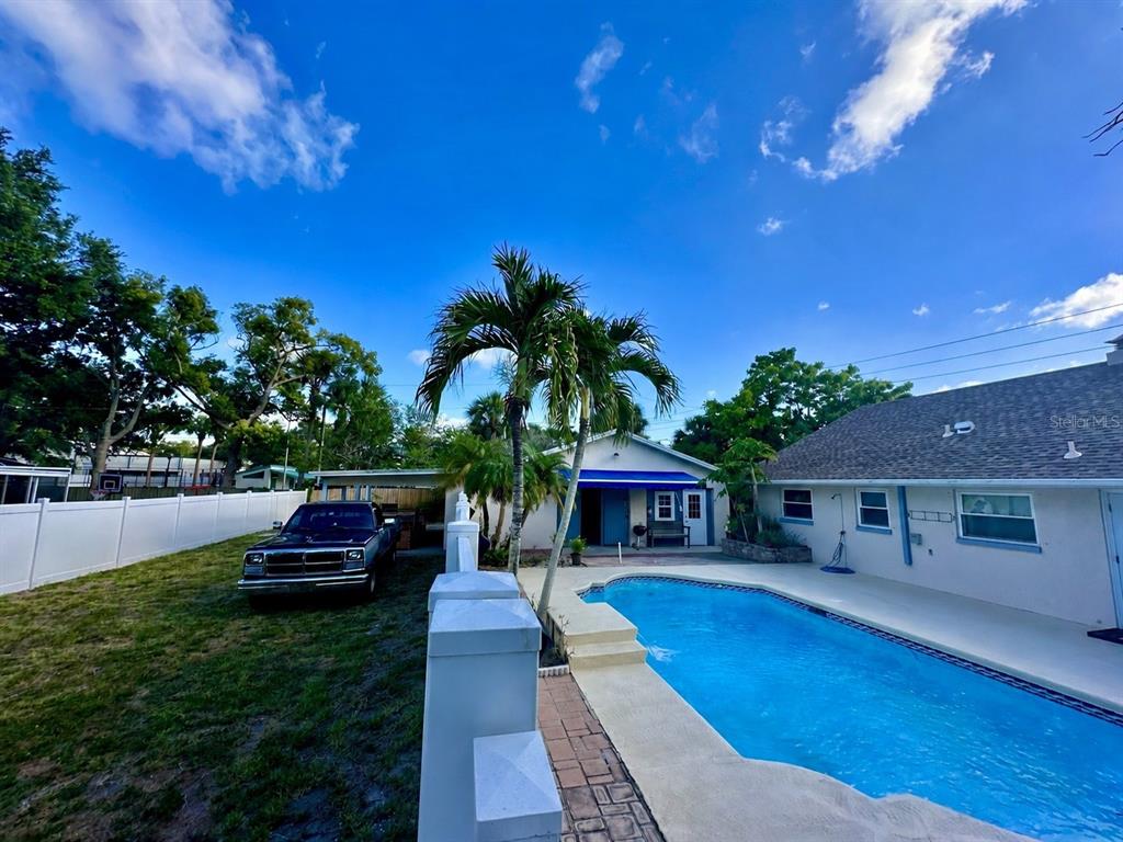 An aerial view shows a backyard with a swimming pool, palm trees, and patio area — 11298 73RD AVENUE N, SEMINOLE, FL