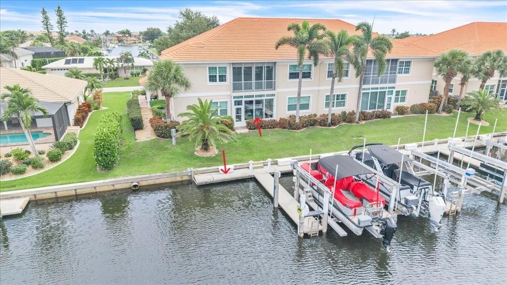 An aerial view of a waterfront condo building with a private boat dock and lawn — 141 TROPICANA DRIVE UNIT 1112, PUNTA GORDA, FL