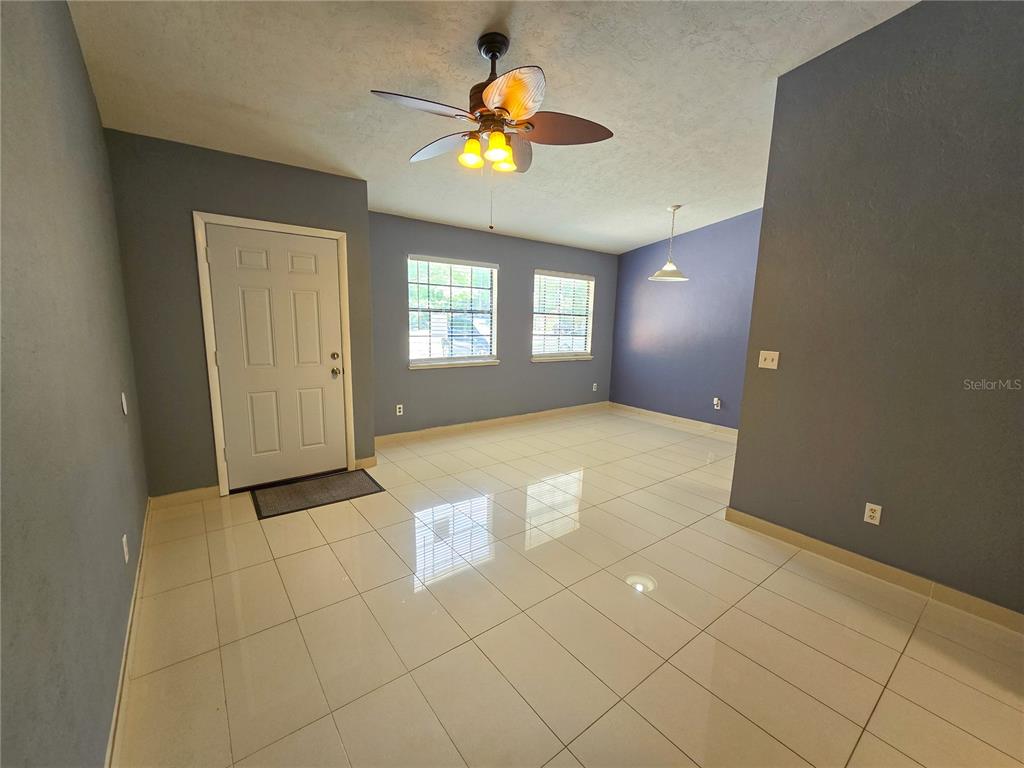 An empty room features light-colored tile flooring, gray walls, a ceiling fan, and two windows — 7030 SW 46TH AVENUE, GAINESVILLE, FL