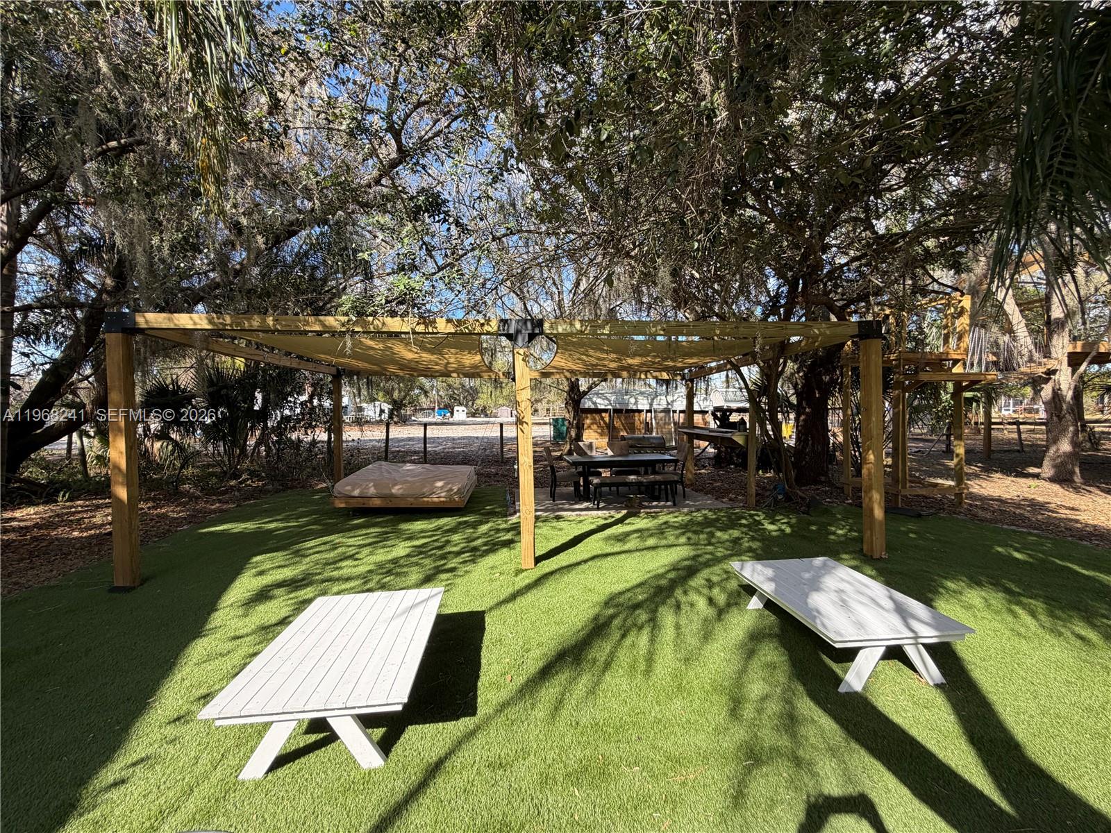 A backyard features a wooden pergola with a shade canopy over a patio and lawn — 4120 Palomino Dr, Sebring FL 33875, SEBRING, FL