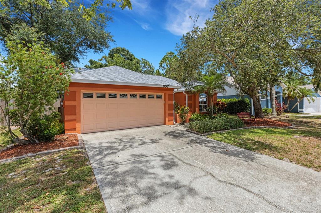 A single-story house with an orange exterior, a two-car garage, and a concrete driveway — 907 50TH STREET E, BRADENTON, FL