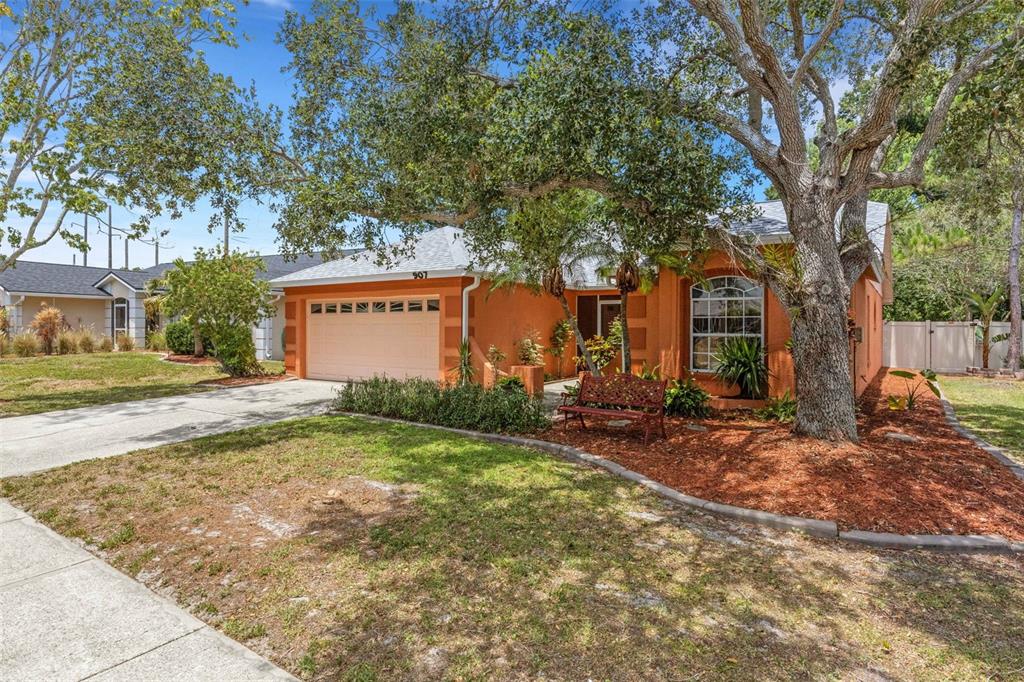 An orange single-story house with a two-car garage and a large tree in front — 907 50TH STREET E, BRADENTON, FL