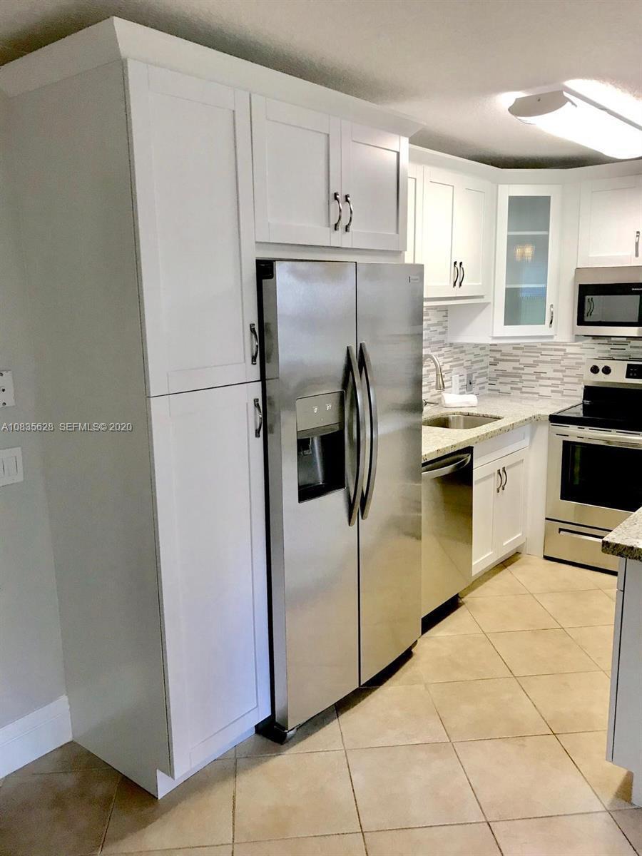 A kitchen features white cabinets, stainless steel appliances, and a tiled backsplash — 86 Mansfield C, Boca Raton FL 33434, BOCA RATON, FL