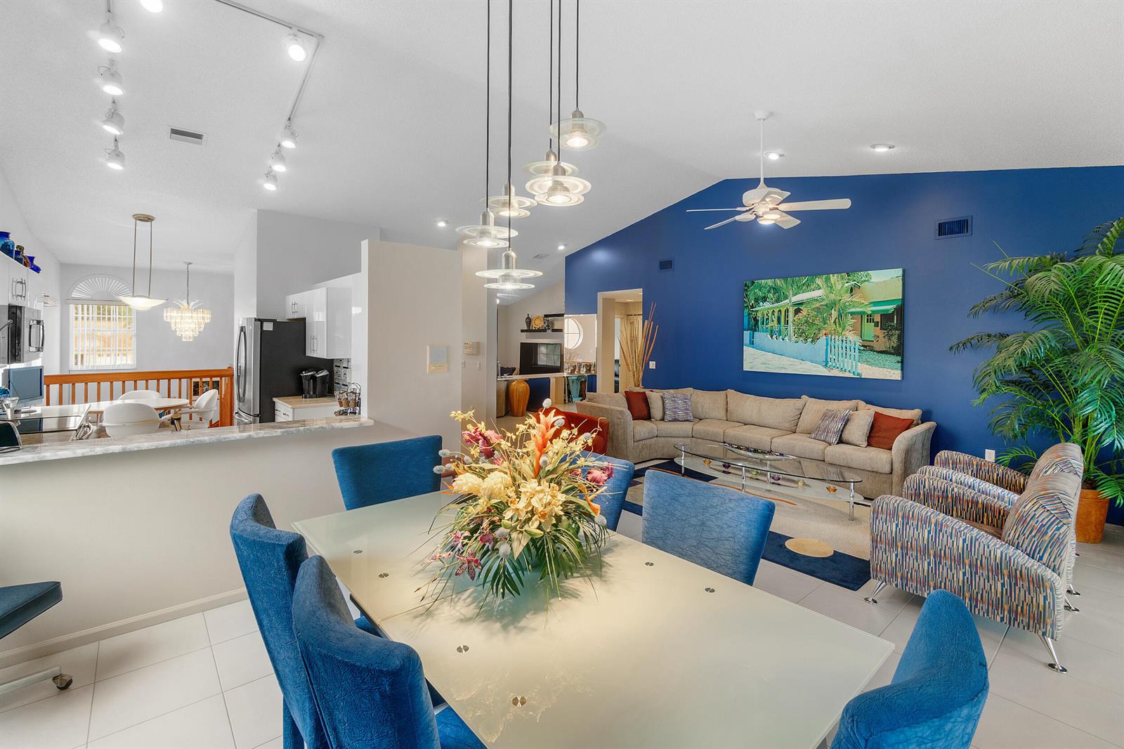 An open-concept living and dining area features a blue accent wall, tile floors, and pendant lighting — 9829 Seacrest Circle # 202, Boynton Beach FL 33437, BOYNTON BEACH, FL