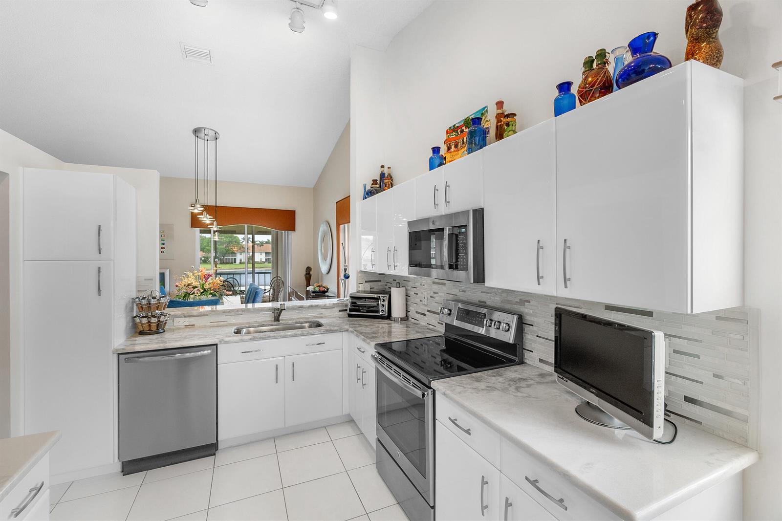A kitchen with white cabinets, stainless steel appliances, and a view of a lake outside — 9829 Seacrest Circle # 202, Boynton Beach FL 33437, BOYNTON BEACH, FL