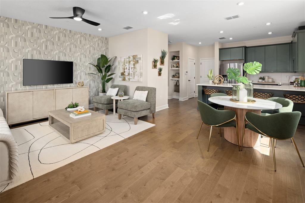 An open-concept living and dining area features hardwood floors, patterned wallpaper, and dark green cabinetry — 2832 CAMELLIA FLOWER STREET, APOPKA, FL