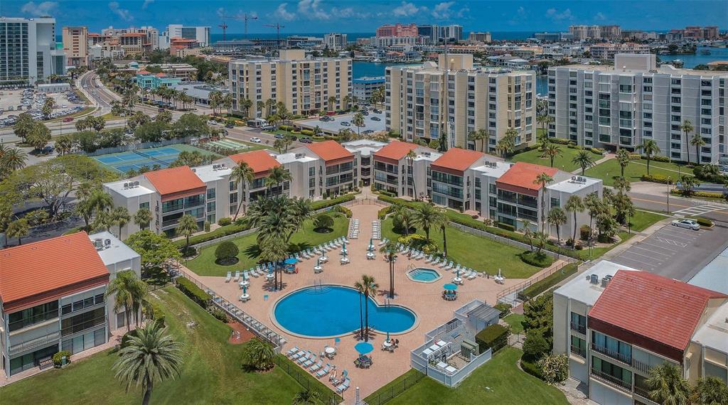 An aerial view of a multi-story apartment complex with a central swimming pool and courtyard — 851 BAYWAY BOULEVARD UNIT 101, CLEARWATER BEACH, FL