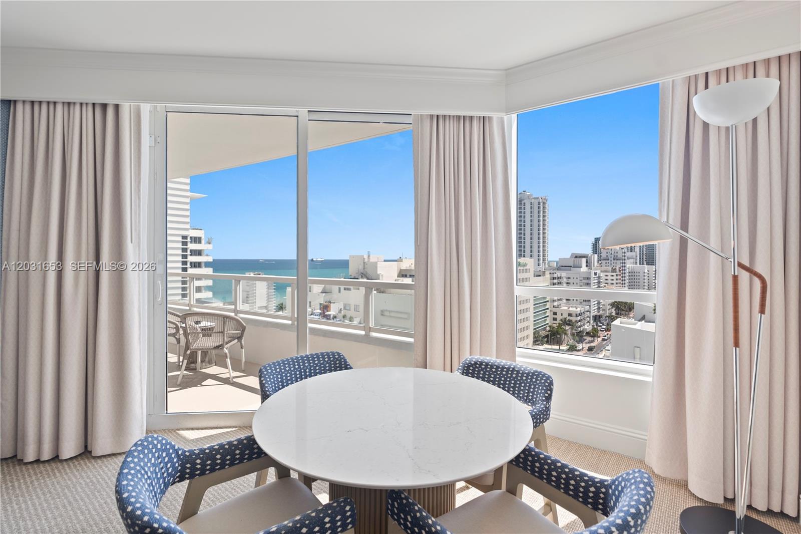 A dining area with a round table and blue chairs overlooks the ocean and city — 4401 COLLINS AV # 1206, Miami Beach FL 33140, MIAMI BEACH, FL