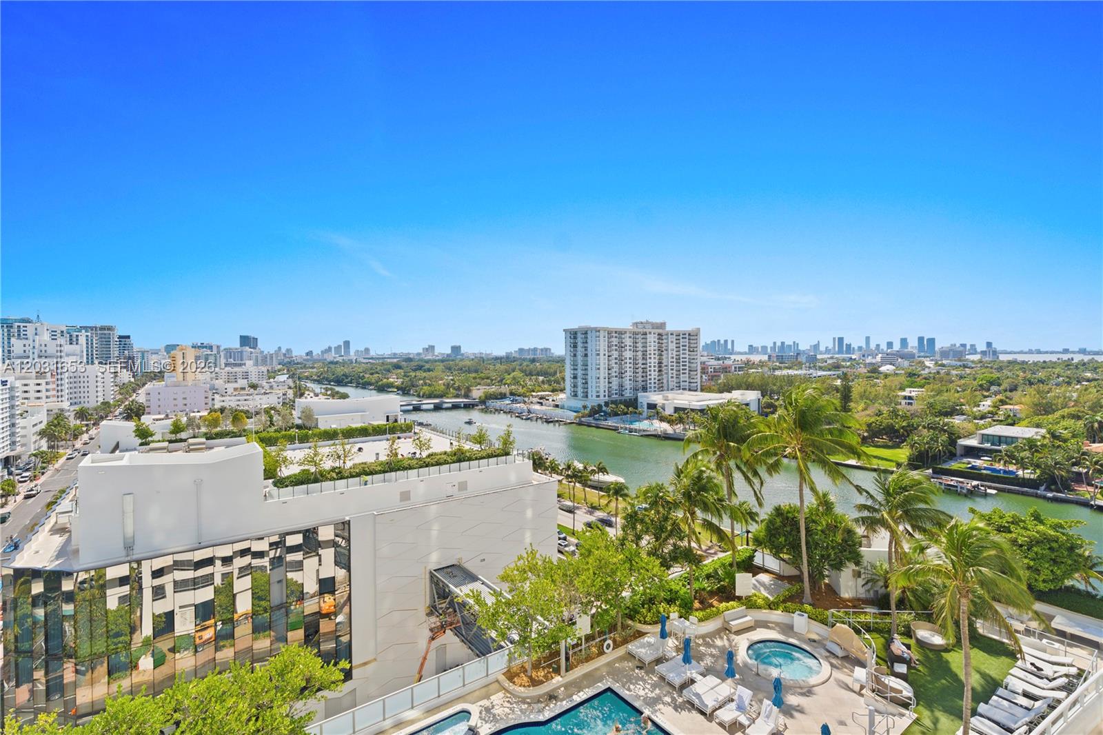 A high-angle view shows a swimming pool, palm trees, a canal, and surrounding city buildings — 4401 COLLINS AV # 1206, Miami Beach FL 33140, MIAMI BEACH, FL