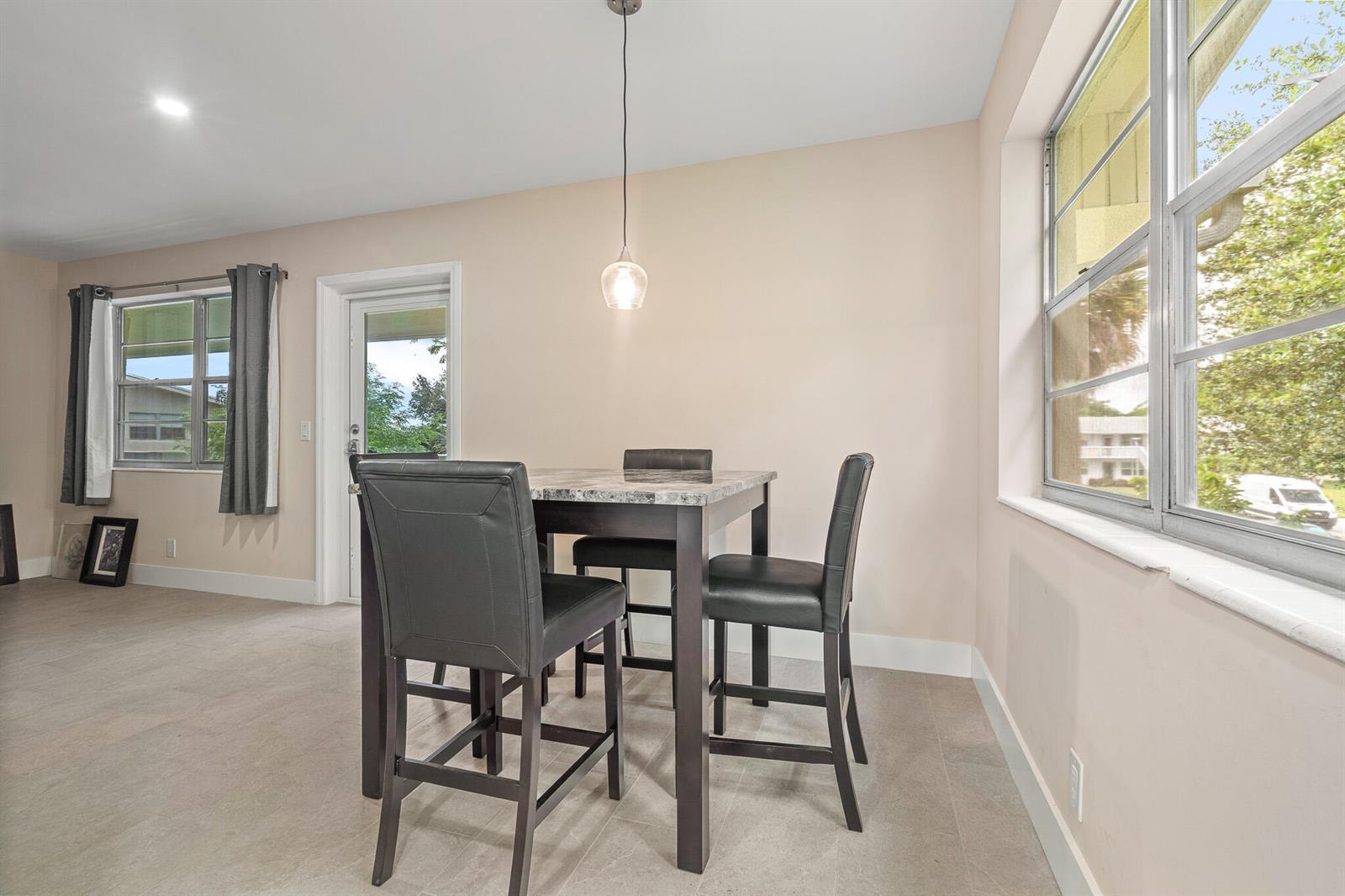 A dining area features a high-top table with four chairs, tile flooring, and large windows — 168 Farnham, Deerfield Beach FL 33442, DEERFIELD BEACH, FL
