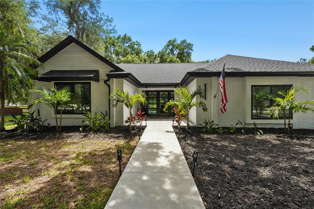 A white brick house with black trim and a concrete walkway leading to the entrance — 906 136TH STREET E, BRADENTON, FL