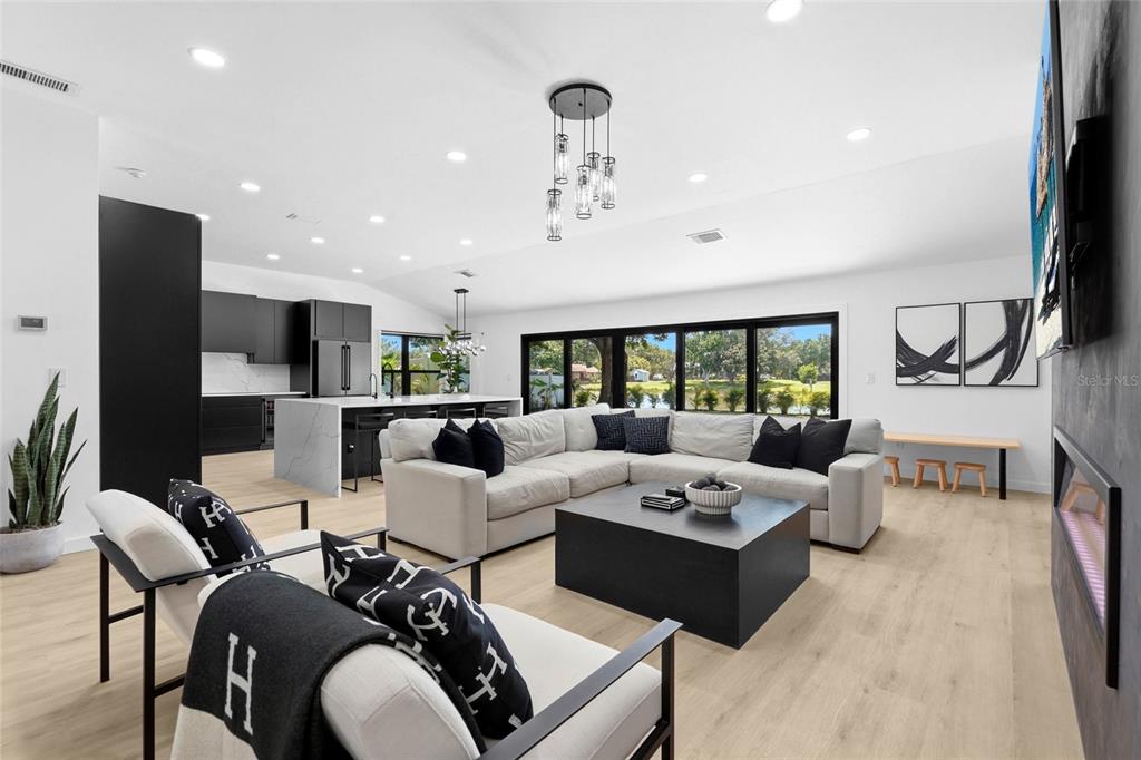 A modern open-concept living room features a white sectional sofa, black accents, and large windows — 906 136TH STREET E, BRADENTON, FL