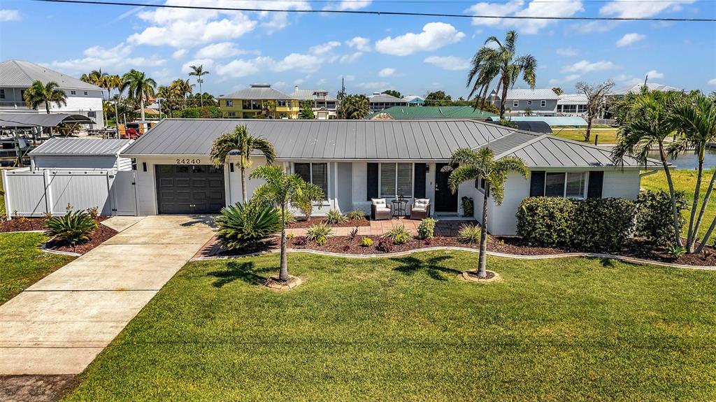 A single-story house with a metal roof, palm trees, and a concrete driveway — 24240 HENRY MORGAN BLVD, PUNTA GORDA, FL
