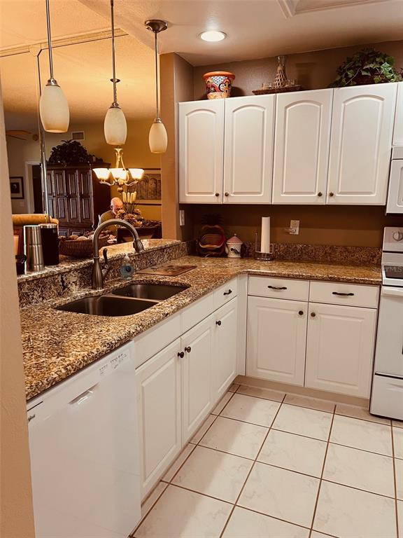 A kitchen features white cabinets, granite countertops, a double sink, and pendant lighting — 8750 OLDE HICKORY AVENUE UNIT 9105, SARASOTA, FL