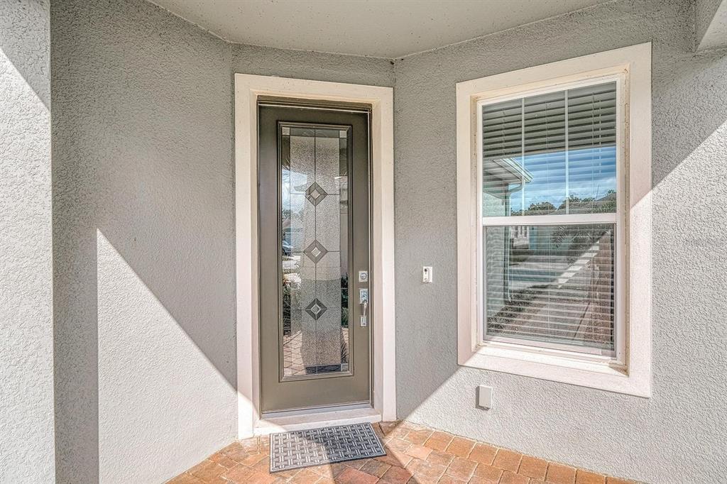 A gray front door with a glass insert sits beside a window on a porch — 2505 CLIFF WAY, ST CLOUD, FL