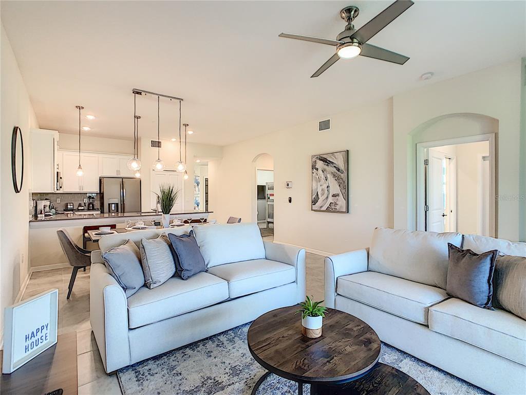 A living room with two light-colored sofas, a round wooden coffee table, and an open kitchen — 763 OCEAN COURSE AVENUE UNIT 763, DAVENPORT, FL