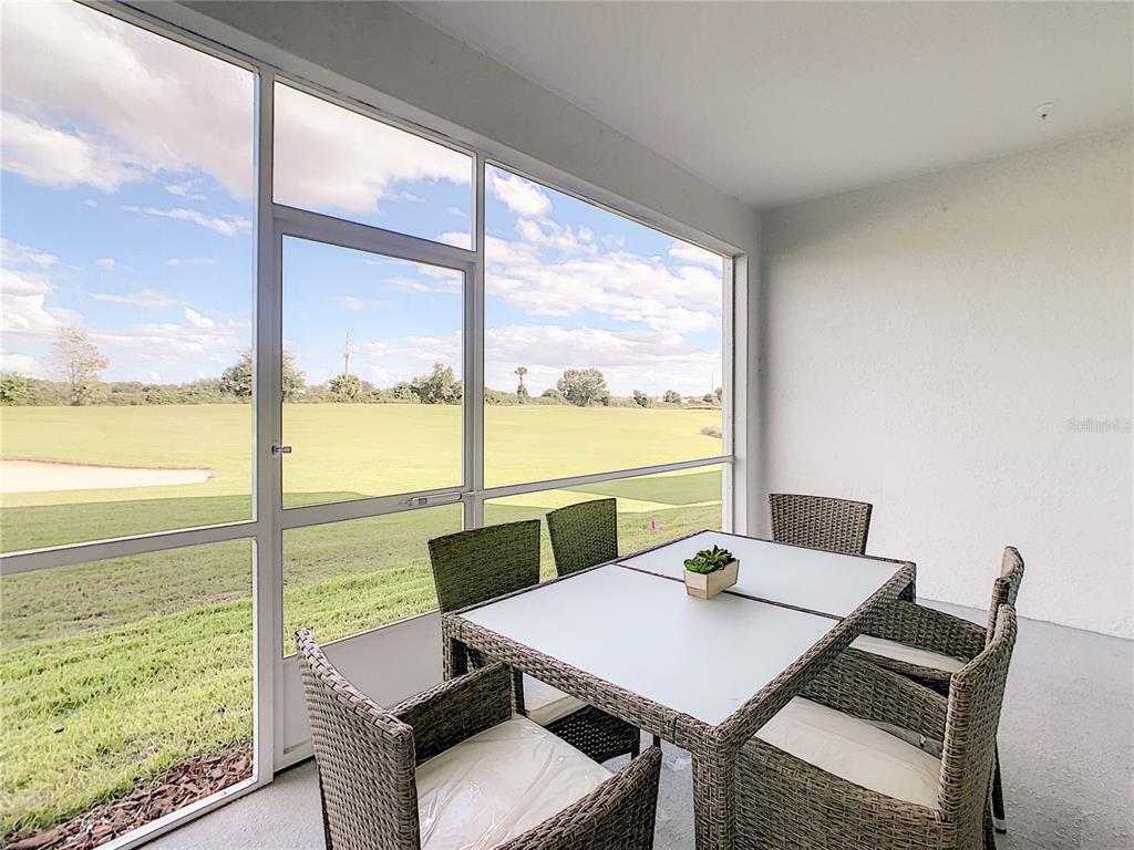 A screened-in patio features a dining set overlooking a golf course — 763 OCEAN COURSE AVENUE UNIT 763, DAVENPORT, FL