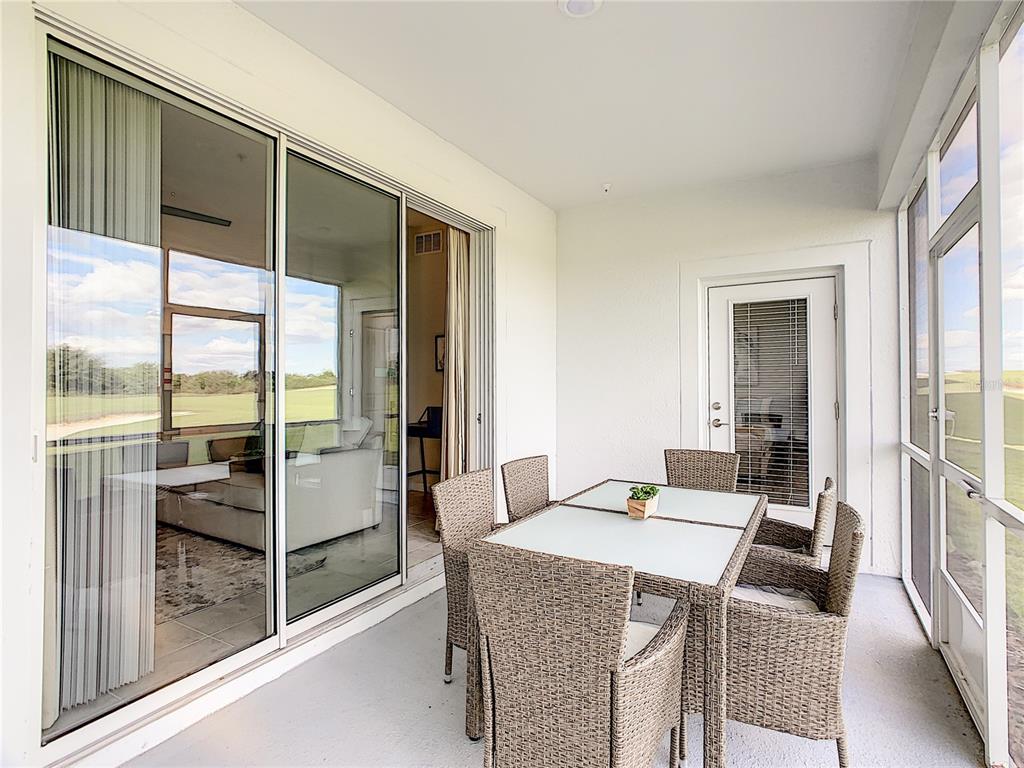 A covered patio features a dining set, sliding glass doors, and a screened-in exterior view — 763 OCEAN COURSE AVENUE UNIT 763, DAVENPORT, FL