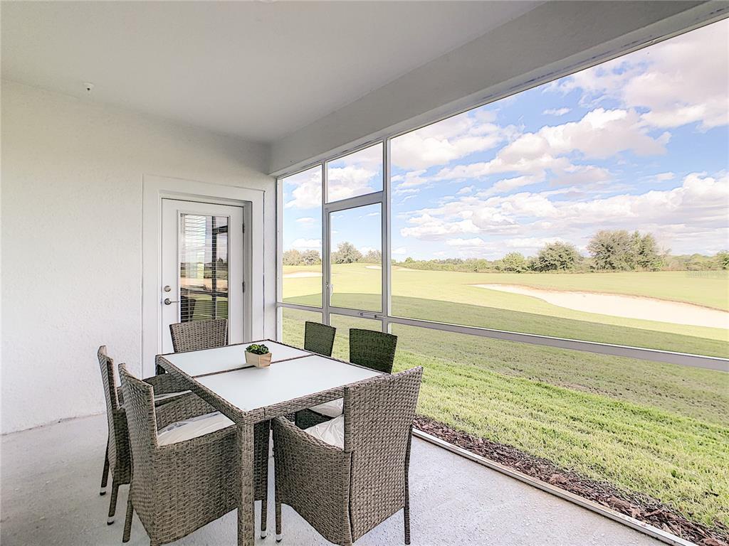 A screened-in patio features a dining set overlooking a golf course with a sand bunker — 763 OCEAN COURSE AVENUE UNIT 763, DAVENPORT, FL
