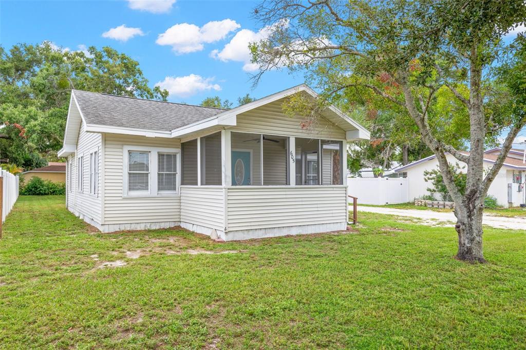 A single-story house with light-colored siding and a screened-in front porch sits on a lawn — 605 3RD AVENUE SW, LARGO, FL