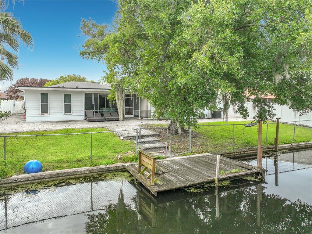 A white house with a patio and a wooden dock sits beside a canal — 2425 LAUDERDALE COURT, ORLANDO, FL