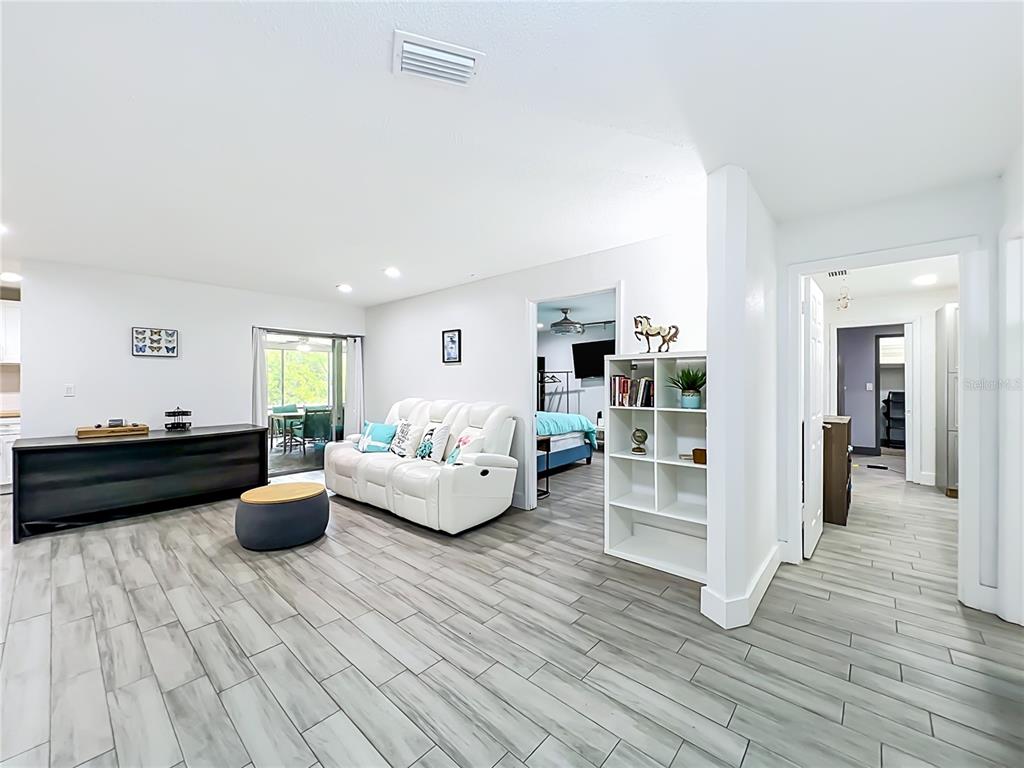 A living room with light wood-look tile flooring, a white sofa, and an open doorway — 2425 LAUDERDALE COURT, ORLANDO, FL