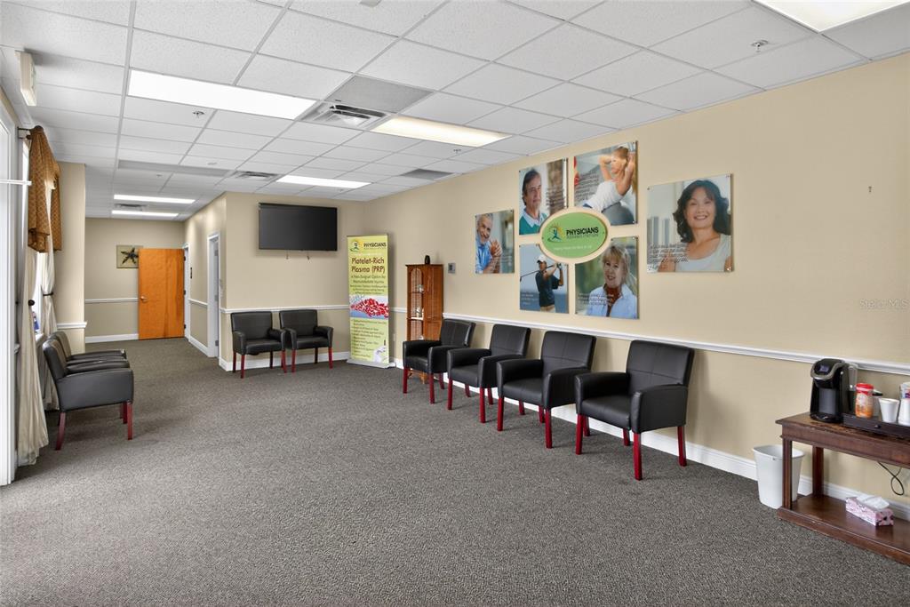 A medical office waiting room features rows of black chairs, beige walls, and carpeted floors — 733 COUNTY ROAD 466, LADY LAKE, FL