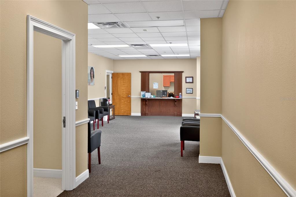 A waiting room features beige walls, a dark carpet, and a wooden reception desk — 733 COUNTY ROAD 466, LADY LAKE, FL