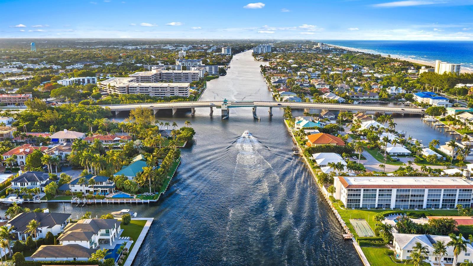 An aerial view of a canal with a bridge, surrounding houses, and the ocean beyond — 964 Eve Street, Delray Beach FL 33483, DELRAY BEACH, FL